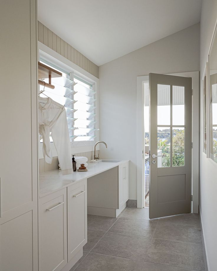 a kitchen with white cabinets and counter tops next to a door that has blinds on it