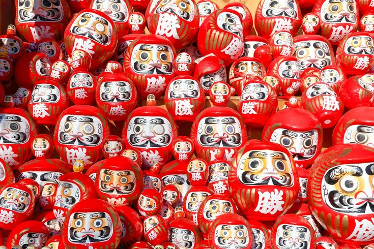 many red and white masks are stacked on top of each other in the shape of skulls