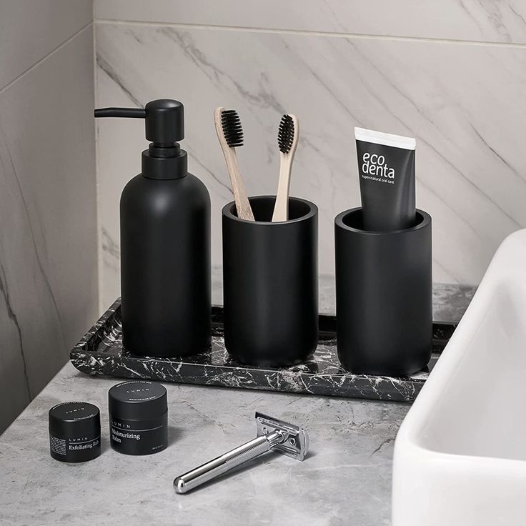 three black bathroom accessories sitting on top of a marble counter