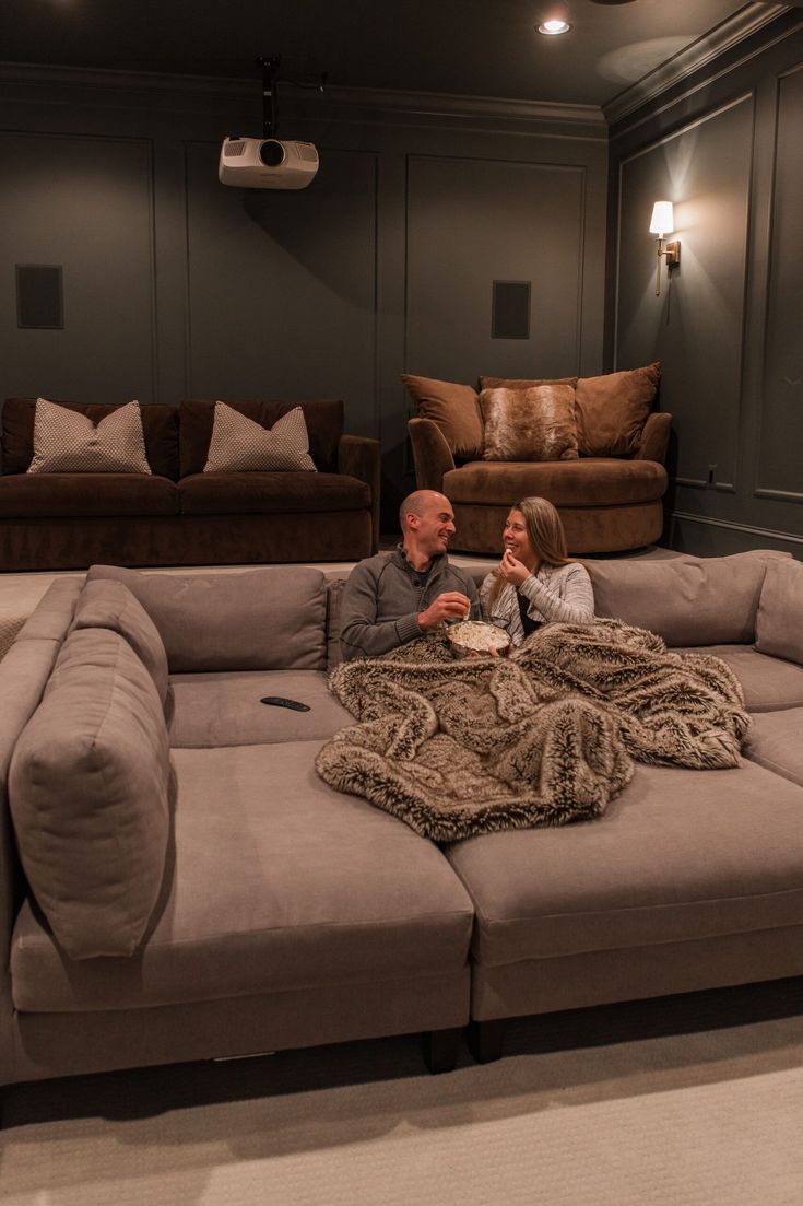 a man and woman sitting on top of a couch in a living room next to each other