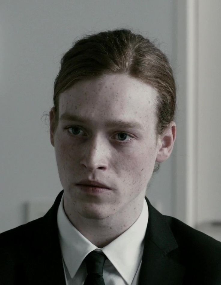 a young man in a suit and tie looking at the camera with serious expression on his face