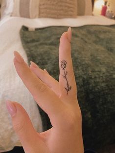 a person's hand with a small flower tattoo on their left thumb and finger