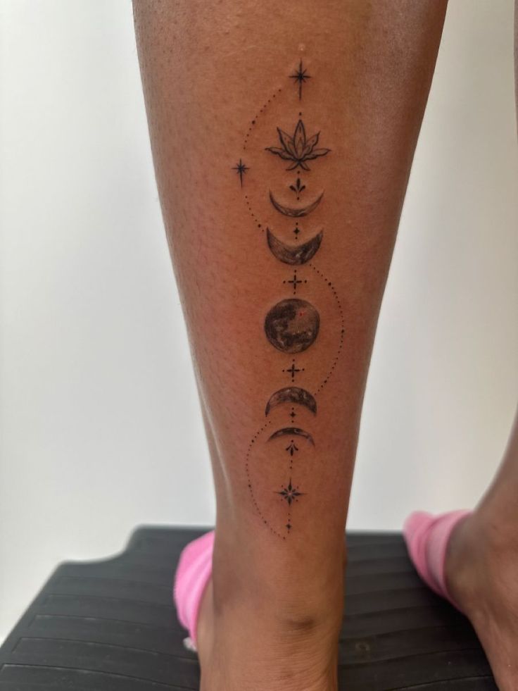 a woman's leg with tattoos on it and the moon, stars, and sun