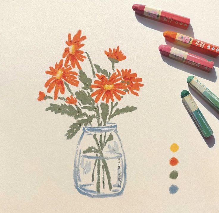 some crayons and markers are next to a drawing of flowers in a vase