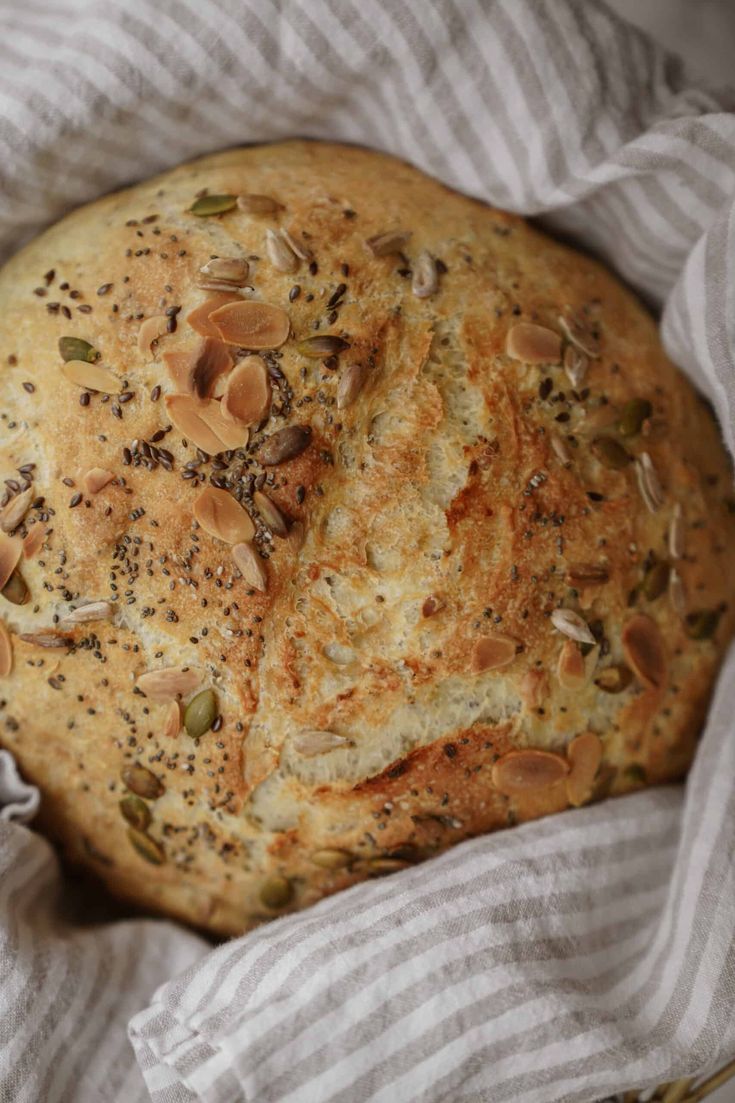 a loaf of bread sitting on top of a white and gray striped cloth covered in nuts