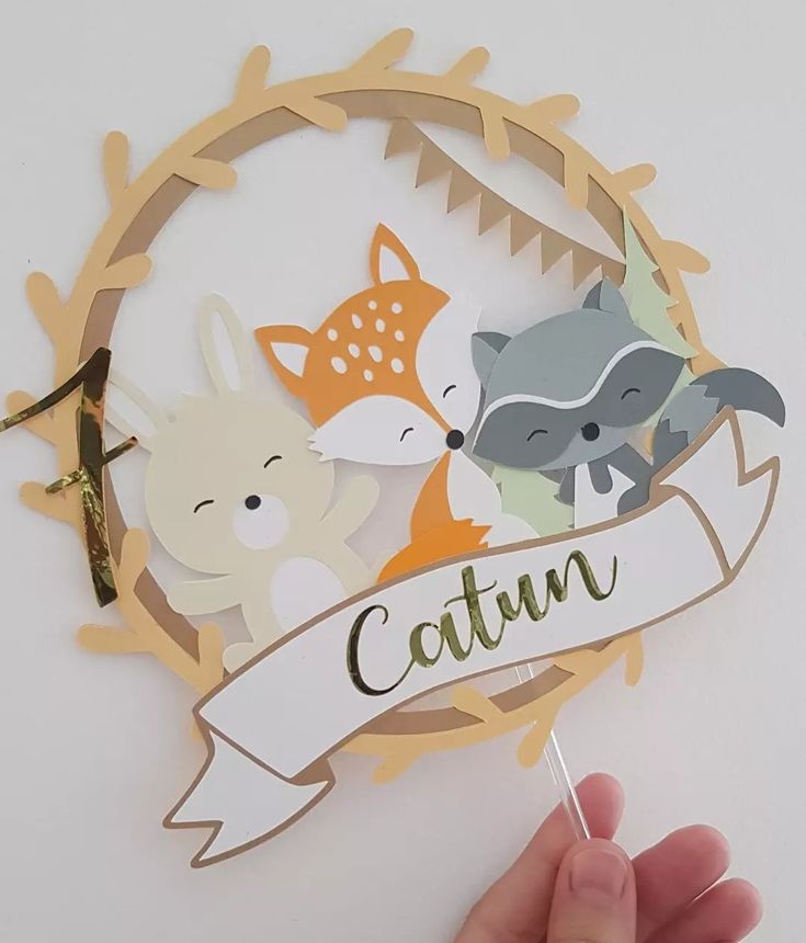 a hand is holding a paper cutout with animals and the word catun on it