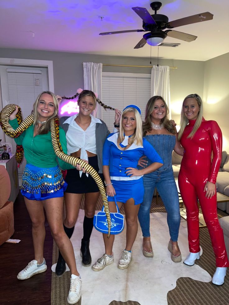 four women dressed in costumes posing for a photo with one holding a snake on her head