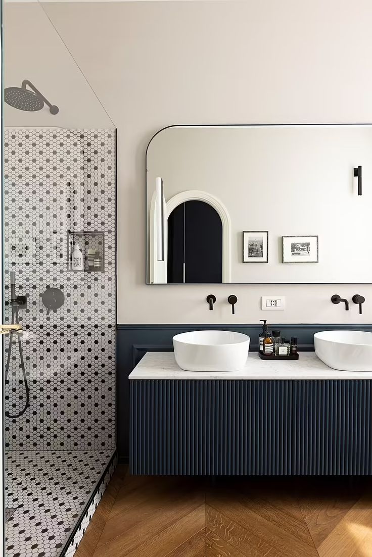 a bathroom with two sinks and a large mirror on the wall next to a walk in shower