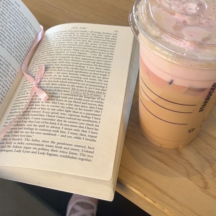 an open book next to a drink on a table