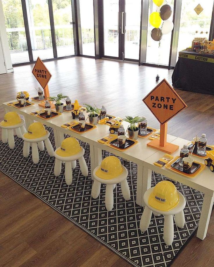 a party table set up with yellow construction hats and desserts on it for an event