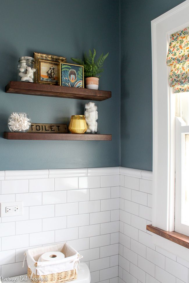 a bathroom with blue walls and white tile on the floor, shelves above the toilet