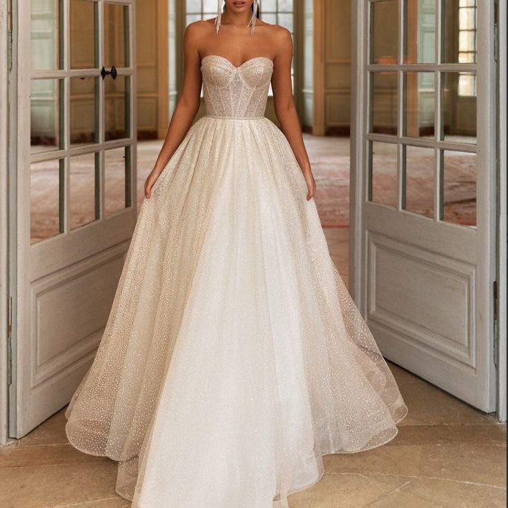 a woman in a wedding dress is standing by an open door and looking at the camera