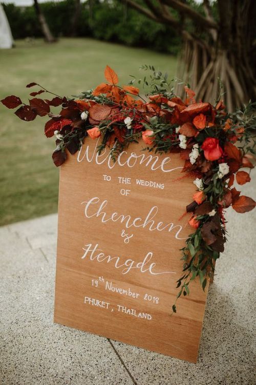 a welcome sign is adorned with flowers and greenery