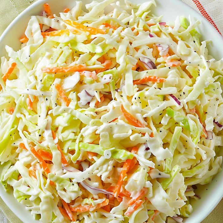 a white bowl filled with coleslaw and carrots on top of a table