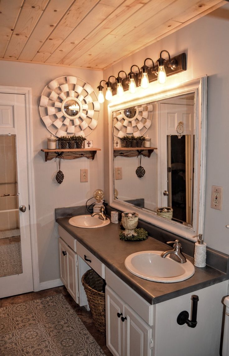 a bathroom with two sinks, mirrors and lights on the wall above them is shown