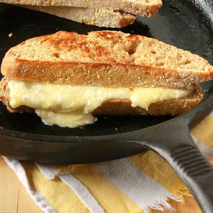 two pieces of bread sitting on top of a black skillet with cheese in it