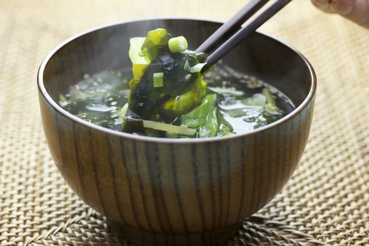 a bowl filled with soup and chopsticks sitting on top of a cloth covered table