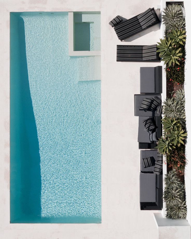 an aerial view of a pool with lounge chairs and plants next to it on the side