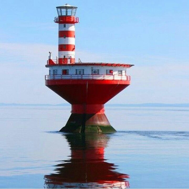 a red and white lighthouse sitting on top of a body of water