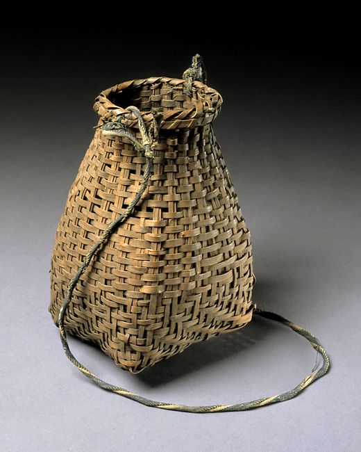 an old woven bag sitting on top of a gray table next to a string cord