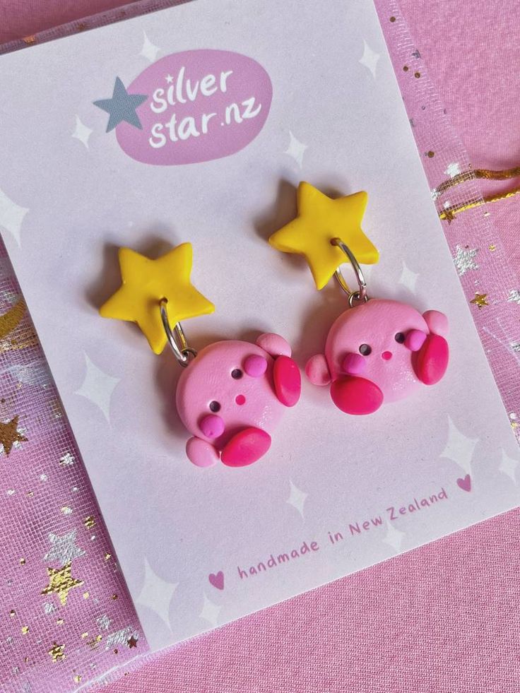 two pink pig earrings with yellow stars on them