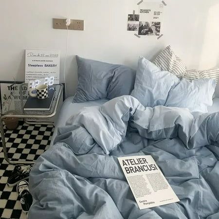 an unmade bed in a bedroom with blue sheets and checkered flooring on the walls