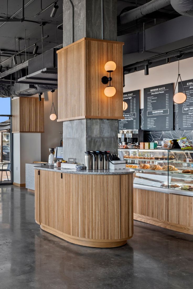 the inside of a bakery with lots of counter space and lights hanging from the ceiling