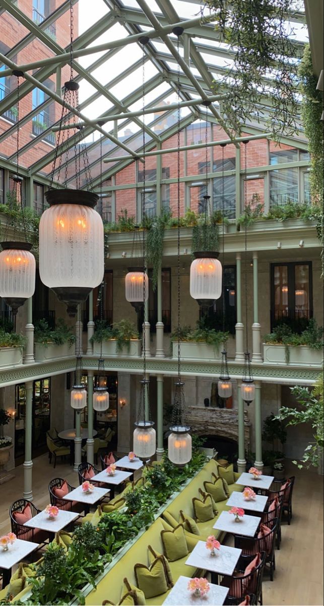 an indoor dining area with tables, chairs and hanging plants in the middle of it