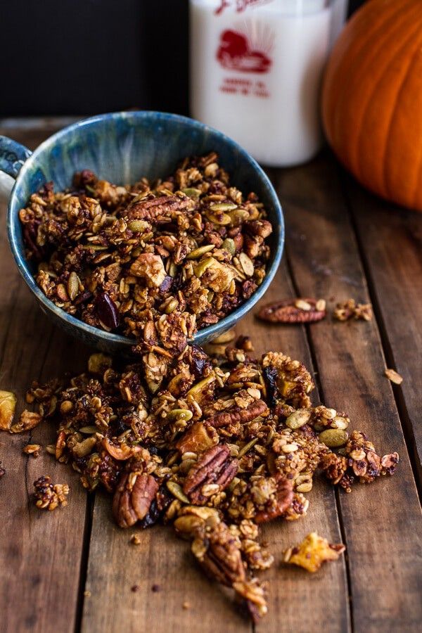 a bowl full of granola sitting on top of a wooden table next to a glass of milk