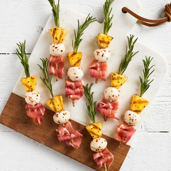 small appetizers are arranged on a cutting board with rosemary garnishes