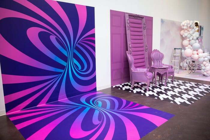 a room with purple chairs and balloons on the wall, in front of an abstract painting