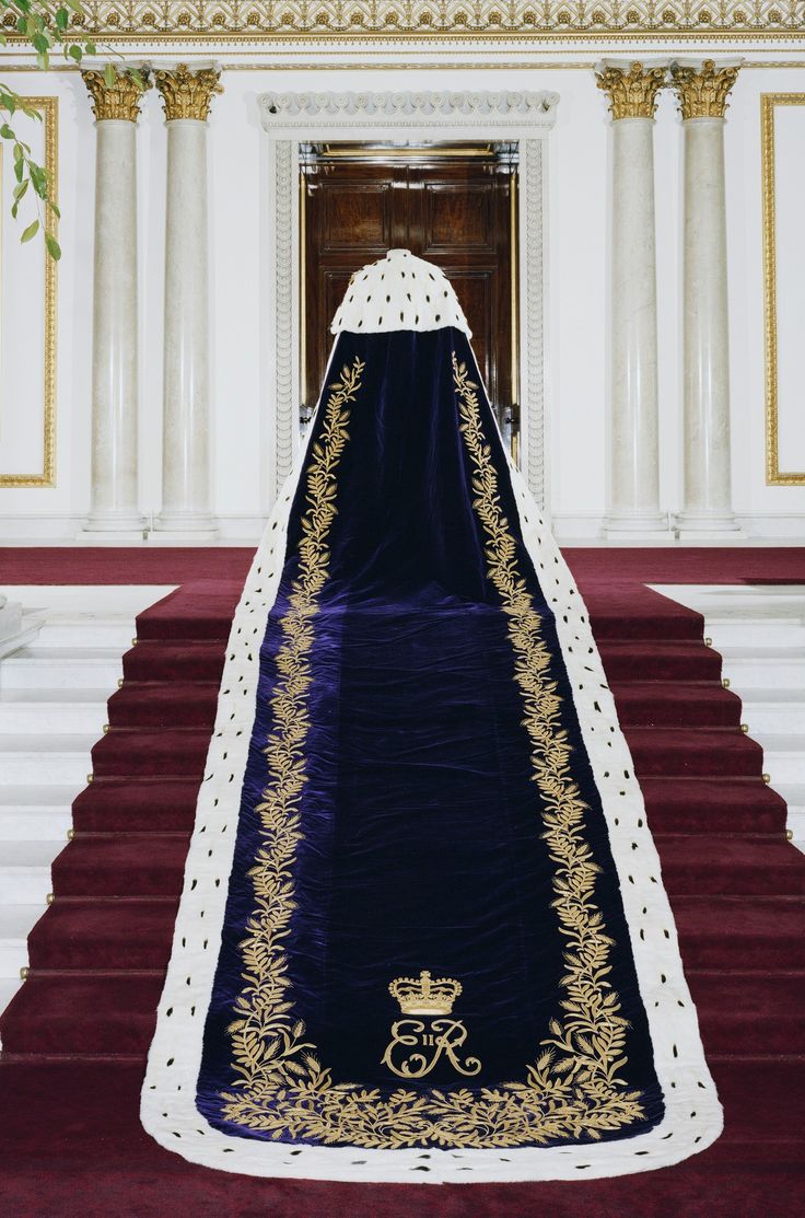 a blue and white wedding gown on display in front of a staircase with red carpet