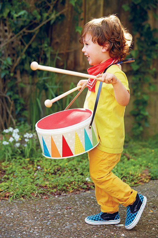 a little boy that is walking with a drum and mallets in his hand,