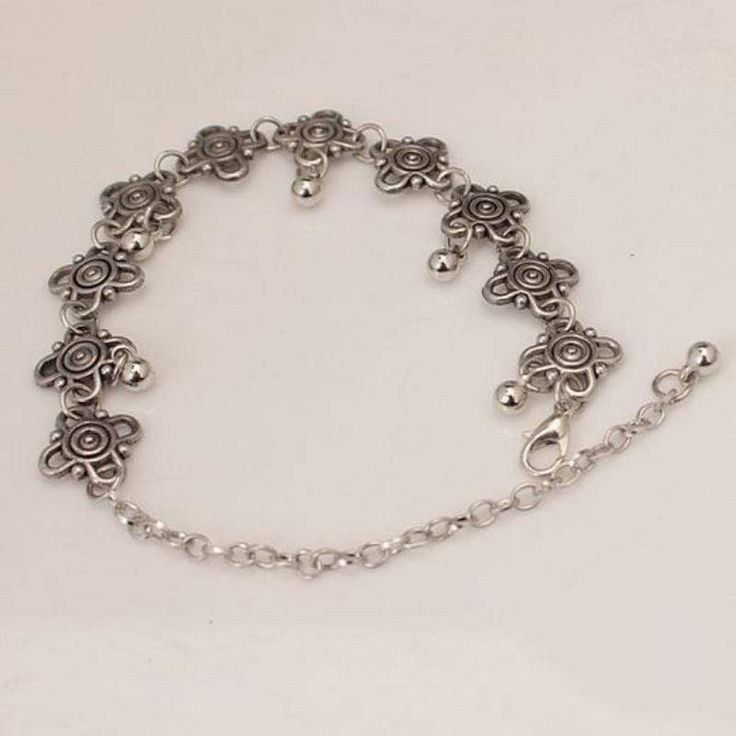 Lovely dainty floral-like charms dance around the ankle with small polished silver beads dangling down along the bottom. Features an adjustable clasp closure. Sold as one individual anklet. Measures approximately 8" with up to 4" of extension chain. Festival Anklets With Adjustable Length, Festival Adjustable Anklets, Elegant Silver Alloy Anklets, Adjustable Silver Anklet With Lobster Clasp, Silver Adjustable Anklets For Spring, Adjustable Silver Anklets For Spring, Silver Charm Bracelet With Adjustable Length, Adjustable Silver Dangle Anklets, Silver Adjustable Dangle Anklets