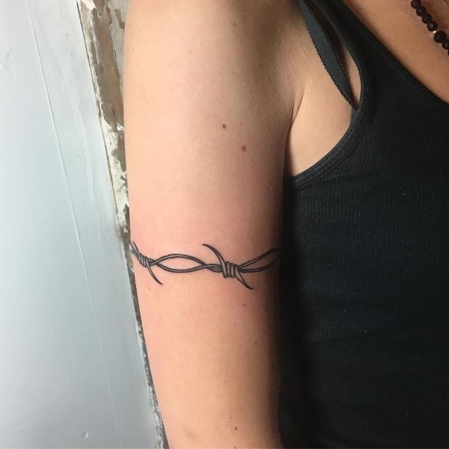 a woman with a tattoo on her arm has a barbed wire wrapped around her arm