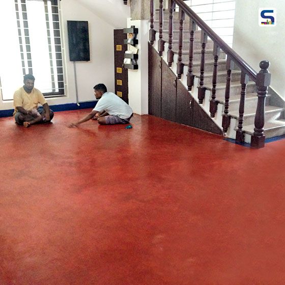 two men are sitting on the floor in an empty room with red floors and stairs