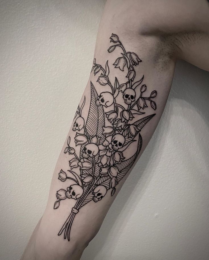 a woman's arm with flowers and skulls on it, in black and white