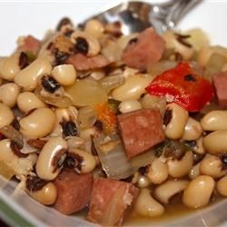 a bowl filled with beans and ham on top of a table