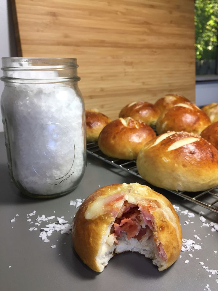 ham and cheese stuffed pretzel rolls on a cooling rack with salt in the background