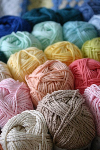 several balls of yarn are sitting in a basket on the floor, all different colors