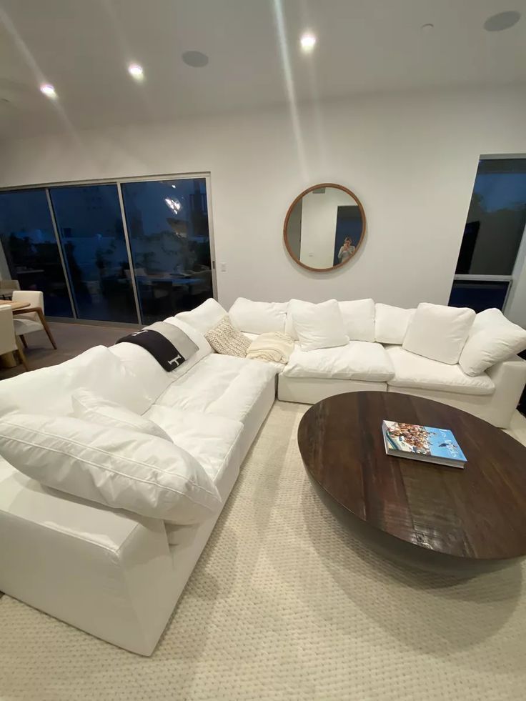 a living room with white couches and large round coffee table in front of sliding glass doors