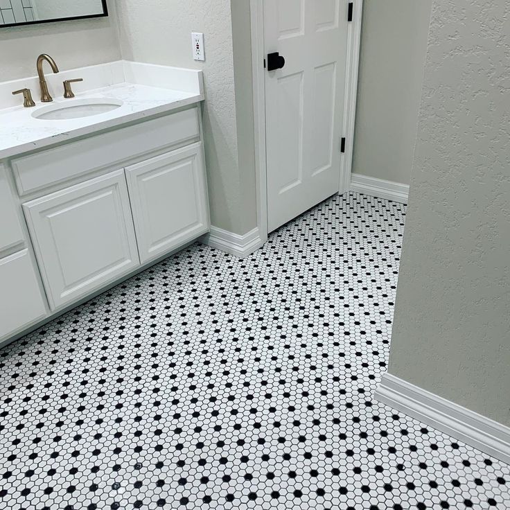 a white bathroom with black and white flooring next to a mirror on the wall