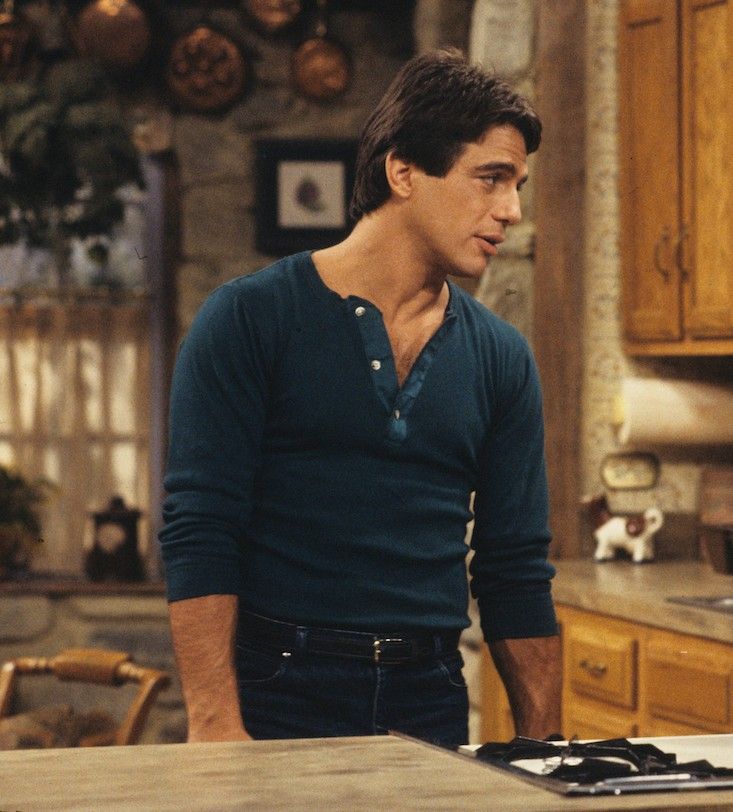 a man standing in front of a stove top oven next to a wooden countertop