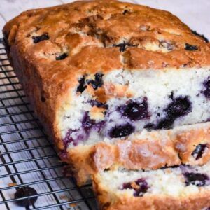 a loaf of blueberry bread sitting on top of a cooling rack