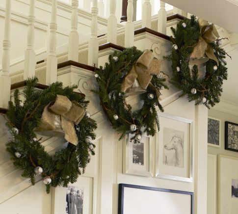 two wreaths are hanging on the wall near pictures and framed photographs in an entryway