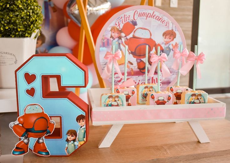 a wooden table topped with cupcakes next to a toy house and other decorations