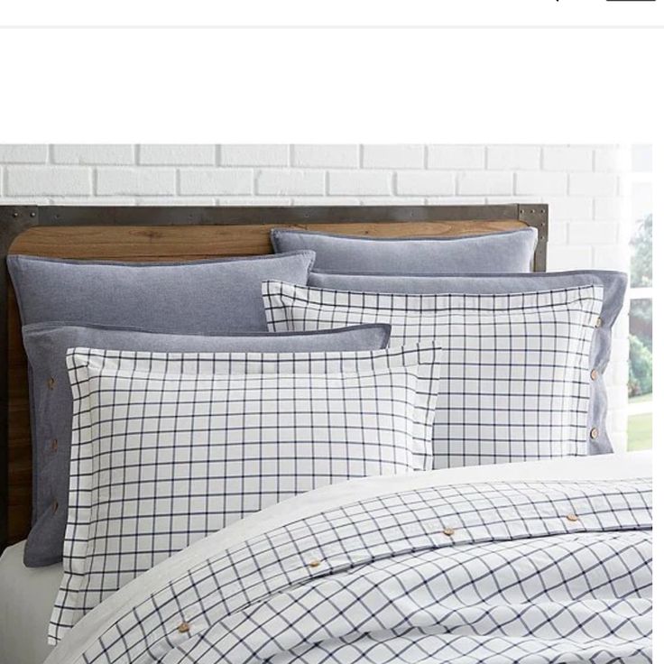 a bed with blue and white plaid comforter set on it's headboard