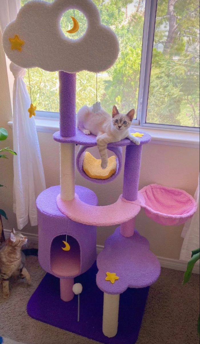 a cat sitting on top of a purple tower in front of a window with stars and clouds