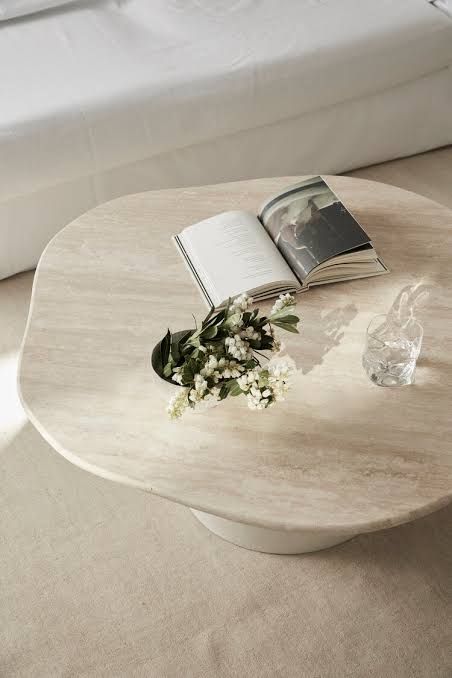 a table with a book and flowers on it in front of a white bedding