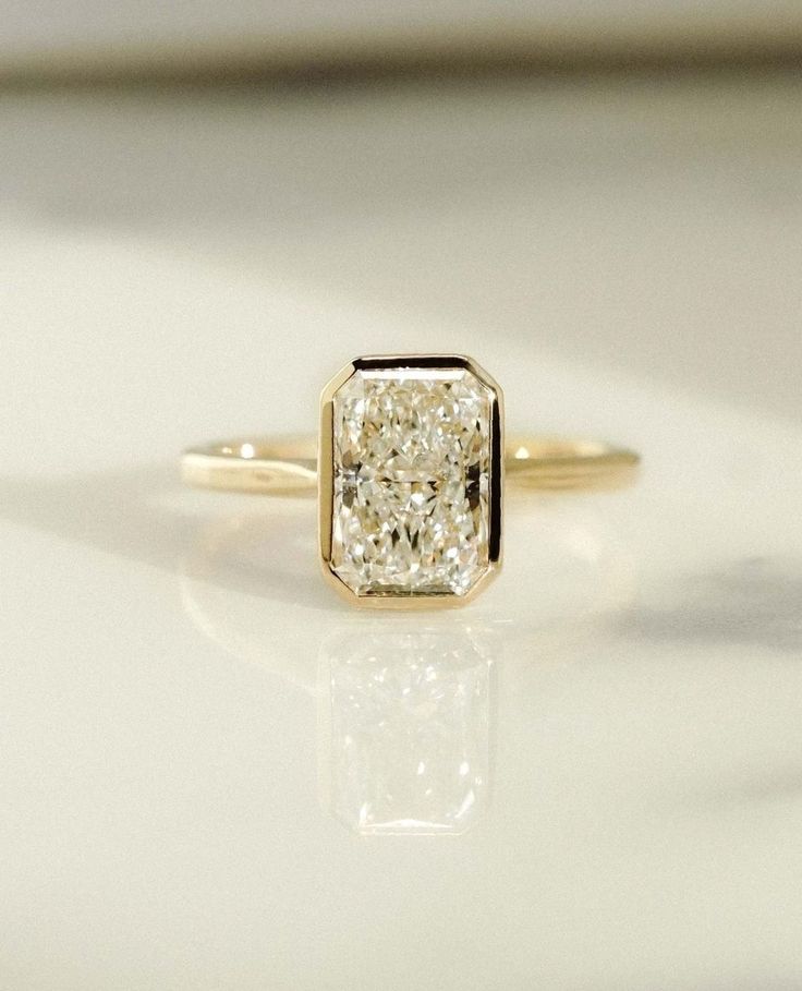 a yellow gold ring with a diamond in the center on a white surface, close up